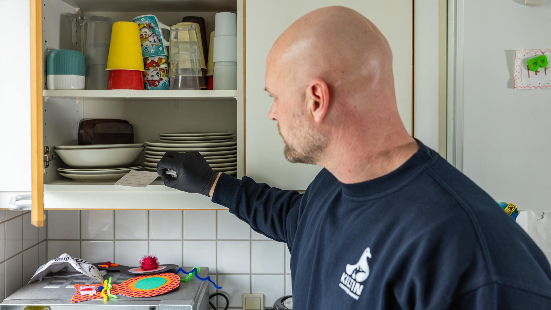En medarbejder lægger et stykke papir i et skab fyldt med service.