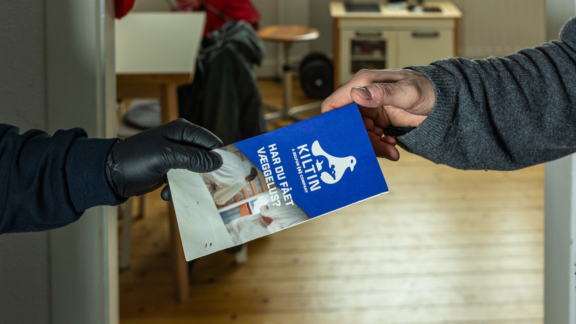 Medarbejder overrækker en flyer til en kunde